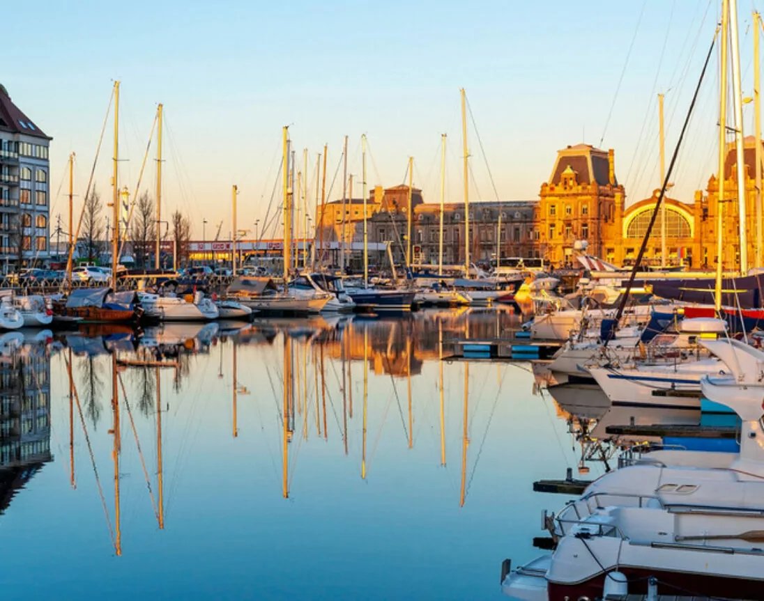 Der Yachthafen von Oostende (Ostende) mit Bahnhof bei Sonnenuntergang, Belgien.