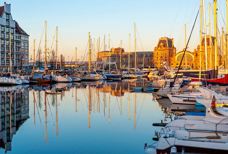 Der Yachthafen von Oostende (Ostende) mit Bahnhof bei Sonnenuntergang, Belgien.