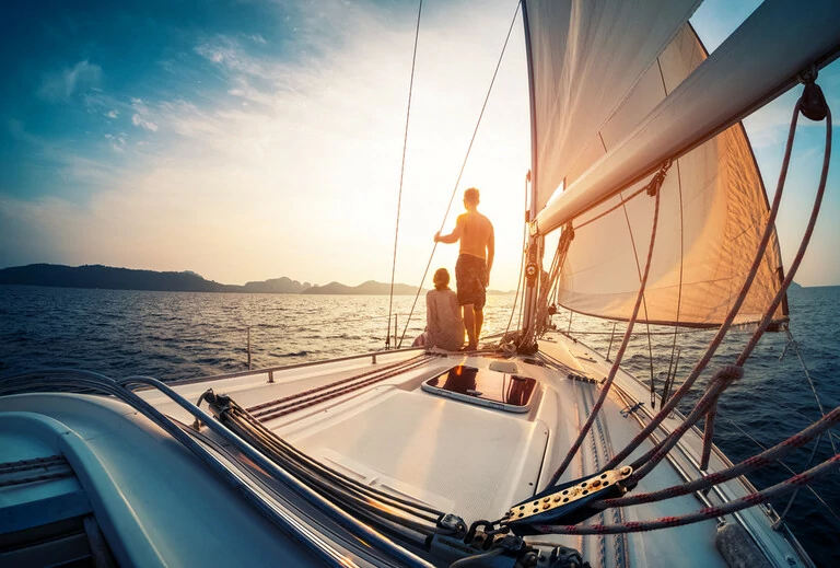 Paar mit Sonnenuntergang vom Deck des Segelbootes, das sich im Meer bewegt