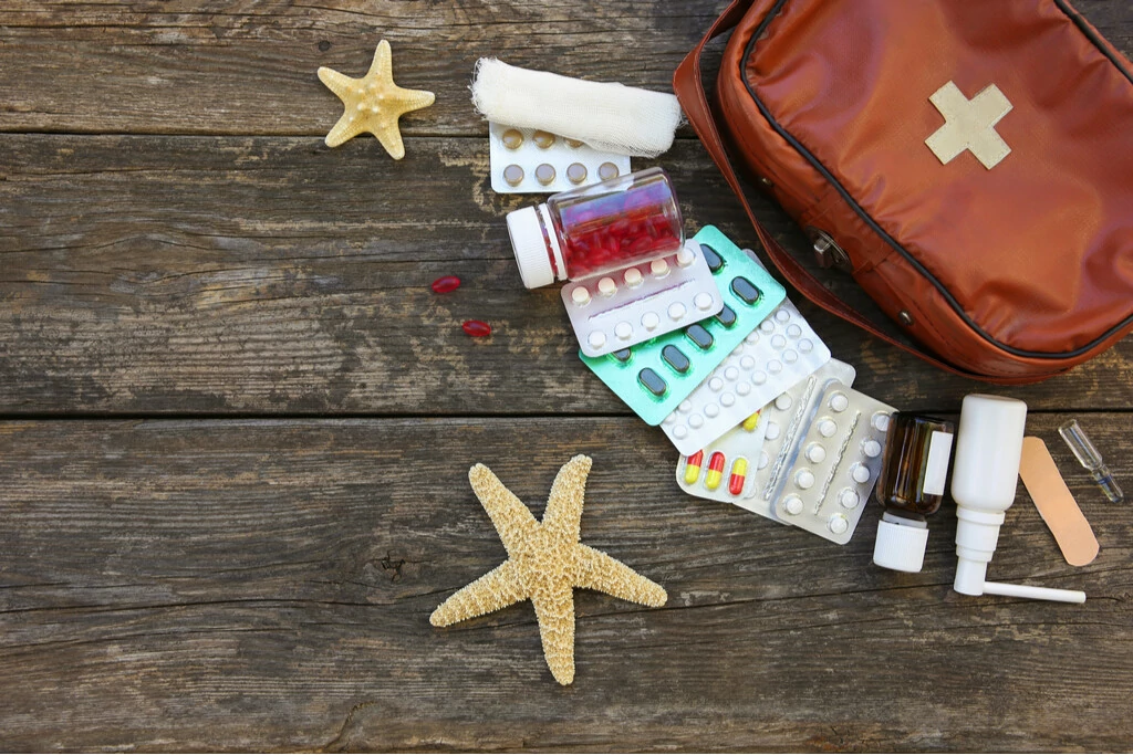 Tabletten neben Koffer für Reiseapotheke