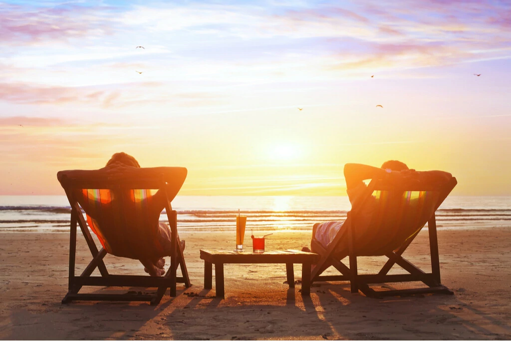 Pärchen genießt Cocktails am Strand bei Sonnenuntergang