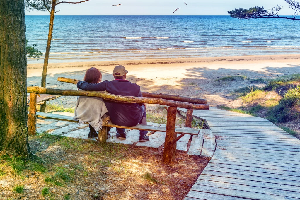 Paar sitzt auf einer Bank am Ostseestrand