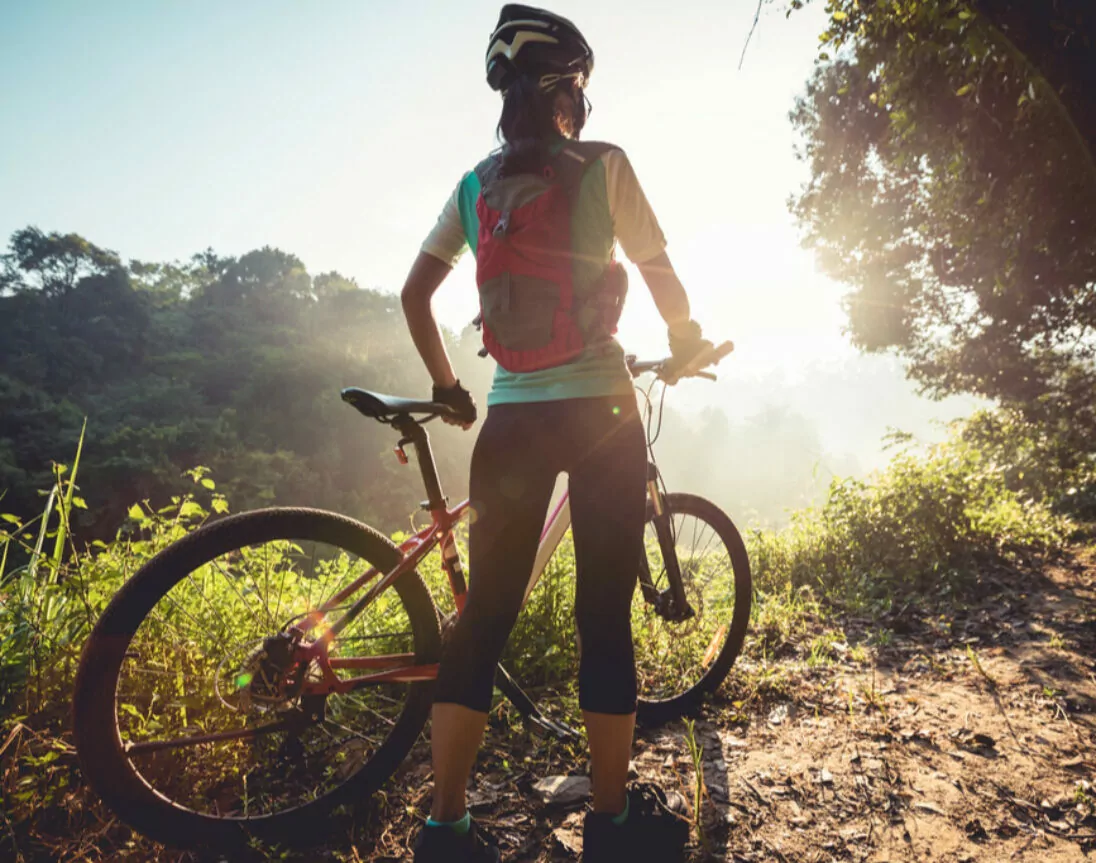 Frau genießt den Ausblick mit Mountainbike von einem Berg