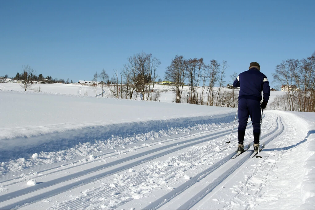 Mann beim Skilanglauf mit Dorf im Hintergrund