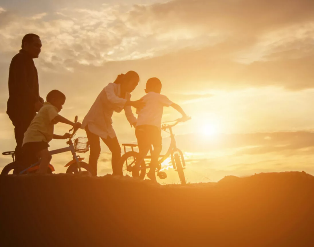Familie zusammen bei Sonnenuntergang mit Fahrrad