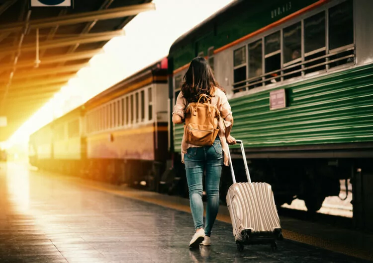 Frau am Bahnhof mit Koffer