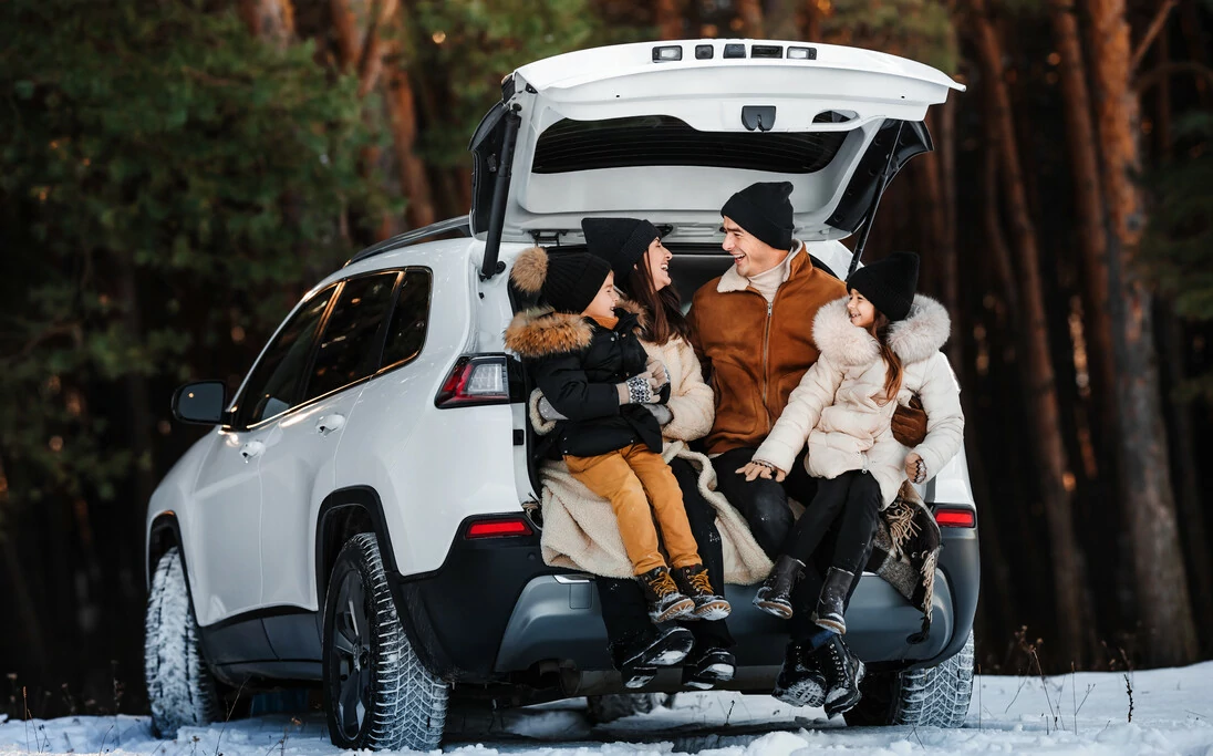 Familie im Ausflug mit Kindern im Winter am Auto