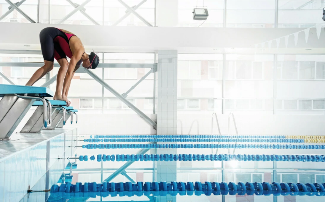 Schwimmerin in Startposition vor dem Sprung in das Wasser