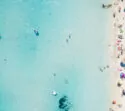 Sandstrand mit Touristen, die im klaren Meer schwimmen